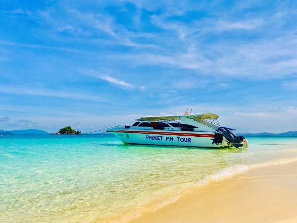 Boat on the beach at Khai Island, surrounded by clear water on a Phuket day trip, ideal for snorkeling and relaxation.